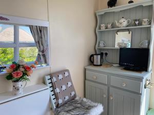 a room with a television and a chair and a window at Hut 4 Ewe glamping pod with shared facilities in Bideford