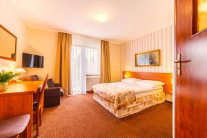 a hotel room with a bed and a desk at Astra Dziwnówek Dom Gościnny in Dziwnówek