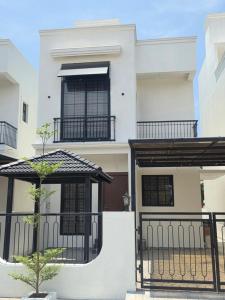 a white house with black gates and a tree at Aqua blue bay villa in Covelong