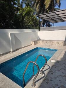 a swimming pool with two metal hand rails next to it at Aqua blue bay villa in Covelong