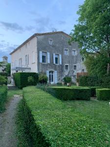 an old stone house with a hedge in front of it at Chateau de Mons Gard prés d Uzes in Mons