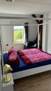 a bedroom with a bed with red sheets and a window at Landhaus Panker in Panker