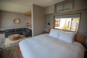 a bedroom with a large white bed and a couch at KAYATSUMA OKINAWA Hotel&Resort in Nakijin +27 photos