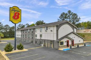 a building with a sign in a parking lot at Super 8 by Wyndham Warner Robins in Warner Robins