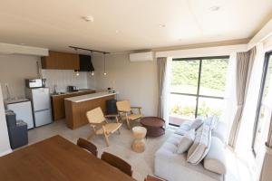 a living room with a couch and a table and a kitchen at KAYATSUMA OKINAWA Hotel&Resort in Nakijin