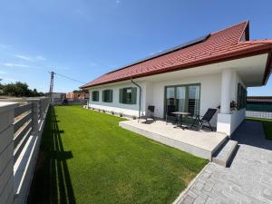 a house with a yard with two chairs and a table at Levendula Apartman in Buzsák