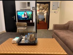 a living room with a couch and a table and a tv at Al Majaridah Hotel in Al Majaridah