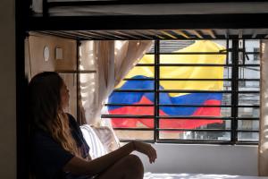 a woman sitting on a bed looking out of a window at Til Sunrise in Cali +9 photos