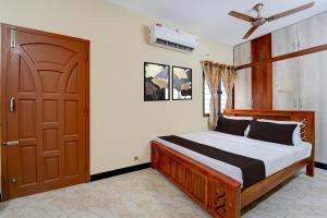 a bedroom with a bed and a wooden door at Super Collection O Madurai Junction Formerly RLR Enclave in Madurai