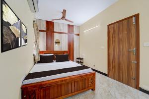 a bedroom with a wooden bed and a wooden door at Super Collection O Madurai Junction Formerly RLR Enclave in Madurai