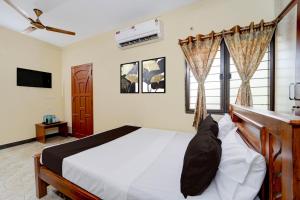 a bedroom with a bed and a tv and windows at Super Collection O Madurai Junction Formerly RLR Enclave in Madurai +40 photos