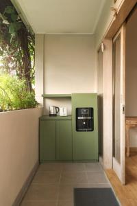 a kitchen with green cabinets and a microwave on a wall at Neduh House Pererenan in Pererenan