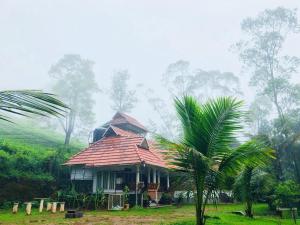 a house with a palm tree in front of it at Traditional Villa Munnar in Anachal