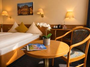 una stanza d'albergo con un tavolo, un letto e una scrivania di Mirage City Hotel Stuttgart Zentrum a Stoccarda