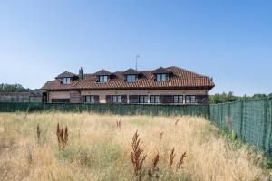 a house behind a fence in a field at Camino Blanco in Ibeas de Juarros