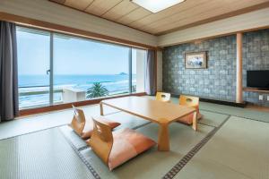 a living room with a table and chairs and the ocean at Kamogawa Grand Hotel in Kamogawa