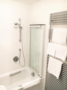 a bathroom with a shower and a bath tub with towels at Hotel Krone in Laudenbach