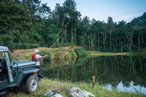 a man fishing in a river with a truck at Urvinkaan - An Estate Hotel Chikmagalur in Chikmagalur