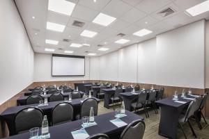 a conference room with tables and chairs and a screen at Meliá Ibirapuera in São Paulo