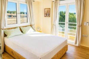 a bedroom with a large white bed with windows at EuZoea Country Home 3 Nature Escape with Pool in Kapandrítion