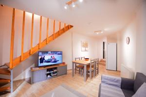 a living room with a television and a dining room table at Nina's House by CorfuEscapes in Doukádes