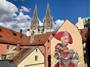 a mural on the side of a building in front of a cathedral at Hotel Münchner Hof und Blauer Turm in Regensburg