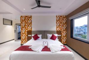 a bedroom with a large white bed with red pillows at Lumis Beach Hotel in Visakhapatnam
