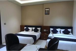 two beds in a room with two chairs and a table at FabHotel The Crystal in Udaipur +12 photos