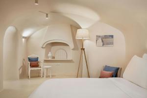 a bedroom with a white bed and a chair at Mystique, a Luxury Collection Hotel, Santorini in Oia +157 photos