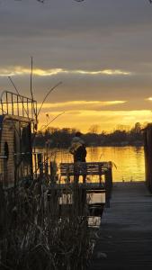a person sitting on a dock with an umbrella at Seeblick Hausboot Sambesi in Königs Wusterhausen