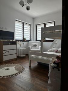 a white bedroom with a bunk bed and a tv at Prázdninový dům MAJKA in Mosty u Jablunkova