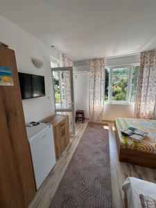 a small room with a bed and a kitchen with windows at Къща за гости "Пердика" in Obzor