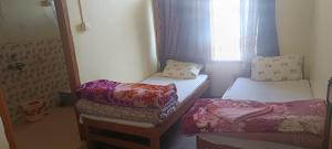 a small room with two beds and a window at Sunrise hotel Tawang in Tawang