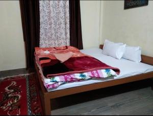 a bed with a red blanket on top of it at Sunrise hotel Tawang in Tawang
