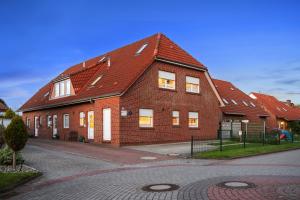 a brick house with a red roof on a street at FroschKönig in Norden