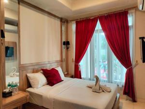 a bedroom with a bed with red curtains and a window at Hotel Indria in Bukittinggi