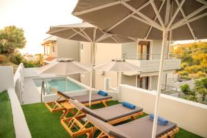 a house with two patio chairs and umbrellas at Erato Superior Suite in Kremasti