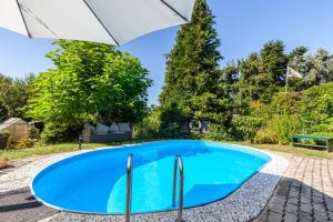 a swimming pool with an umbrella in a yard at Ferienwohnung Elbtalblick in Weinböhla