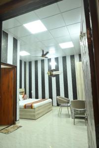 a bedroom with a bed and chairs and a ceiling at Mansa Lawn & Resort in Lucknow