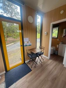 a room with a table and chairs in front of a door at Gum Tree by Tiny Away in Dixons Creek