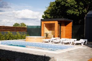 a swimming pool with white chairs and a house at Давидів Хутір in Zhytomyr