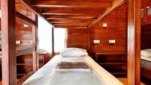 a bedroom with a bed in a room with wooden walls at Gili Buana Hostel & Backpackers Gili Air in Gili Islands