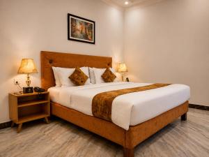 a bedroom with a large bed and a nightstand with two lamps at Lawrence View Hotel, Lahore in Lahore