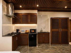 a kitchen with wooden cabinets and a black refrigerator at Lawrence View Hotel, Lahore in Lahore
