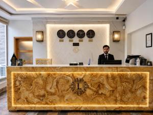 a man in a suit sitting at a reception desk at Lawrence View Hotel, Lahore in Lahore