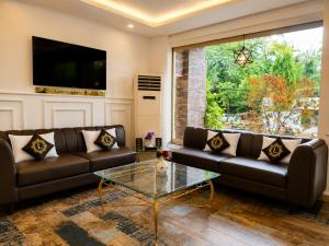 a living room with two leather couches and a glass table at Lawrence View Hotel, Lahore in Lahore