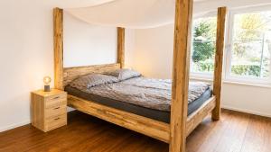 a wooden canopy bed in a bedroom with a window at Swiss Horizon - Mythenblick - Modern 100m2 mit Alpenblick und Terrassen in Hinwil