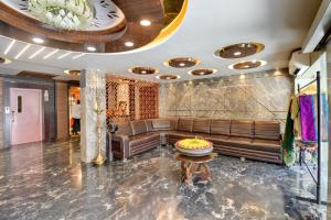 a lobby with a leather couch and a table at Hotel Bhagyalaxmi in Shirdi