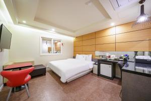 a hotel room with a white bed and a red chair at Busan Gwangalli Nuri Hotel in Busan