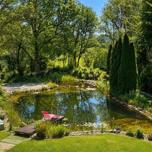 a garden with a pond with a red bench in it at Villa Kirnach Private Spa Retreat im Allgäu in Biessenhofen +61 photos